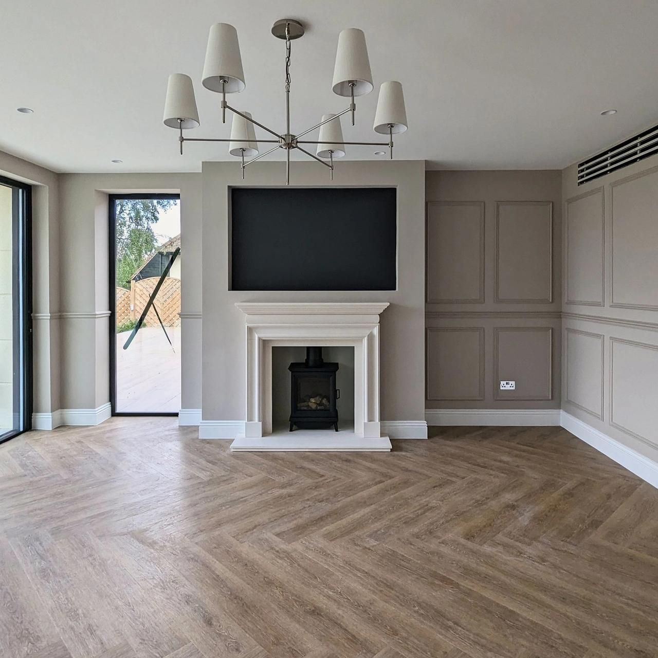 Living room fireplace wall with painted panelling either side of a stone surround and a pendant above