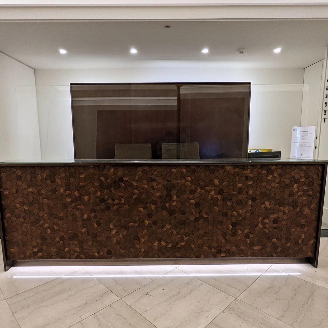Reception desk with a patterned front under a painted ceiling with downlights