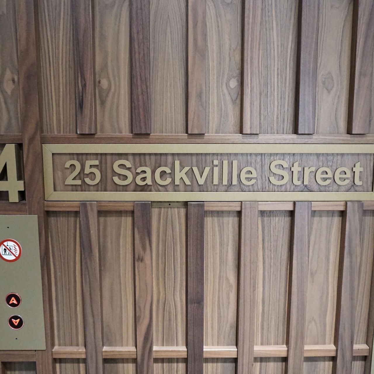 Walnut lift lobby wall with a brass Sackville Street sign and the number 4 for the floor