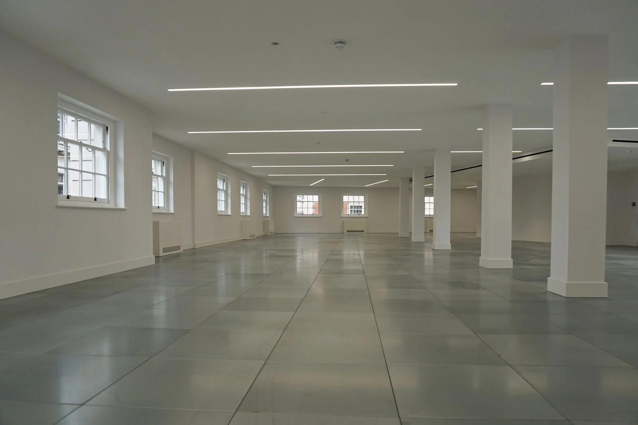 Finished office floor at Sackville Street with white walls and columns, a grey tiled floor and sash windows along both sides