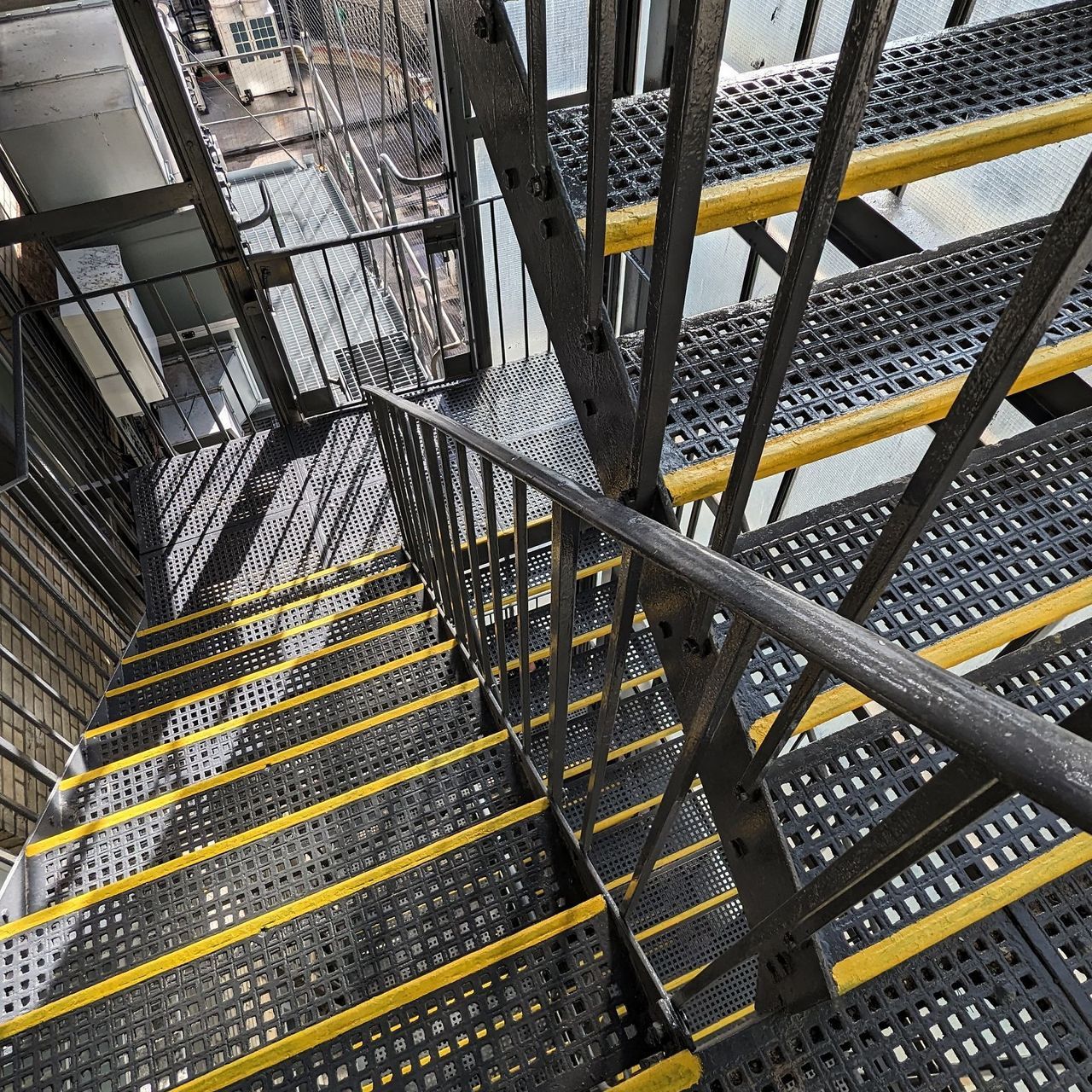 External steel fire escape stair with yellow tread edges seen from above