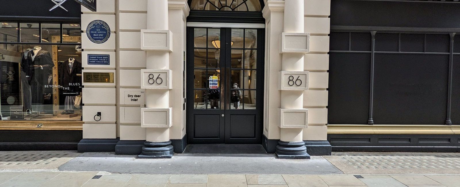 Stone entrance on Jermyn Street with fluted pilasters, a fanlight and black painted double doors