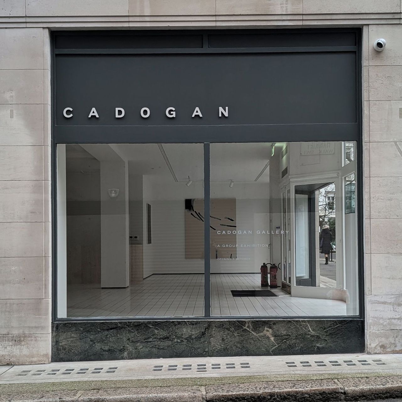 The finished shopfront in daylight, dark grey fascia and reveals against pale stone with a dark green stone stallriser