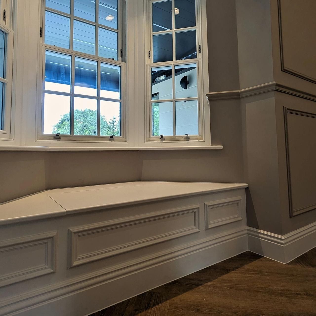Bay window seat with painted panelling below the sashes and a view over the garden