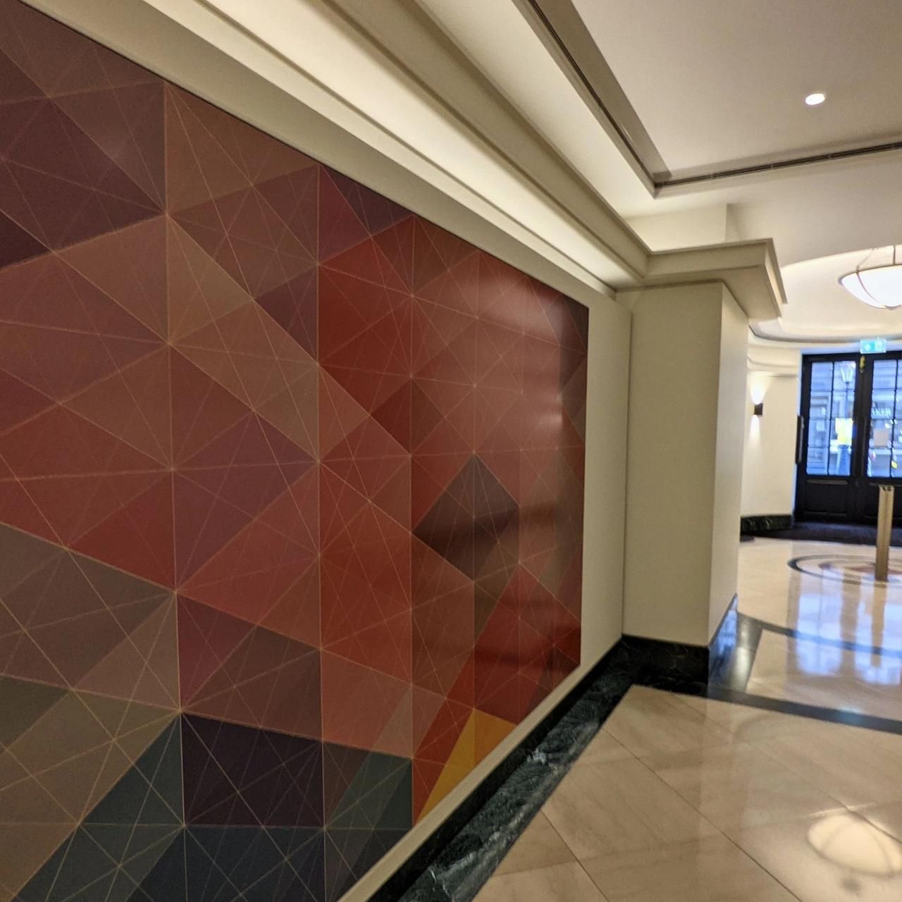 Geometric mural in reds and blues on a wall by the entrance, painted walls and ceiling around it
