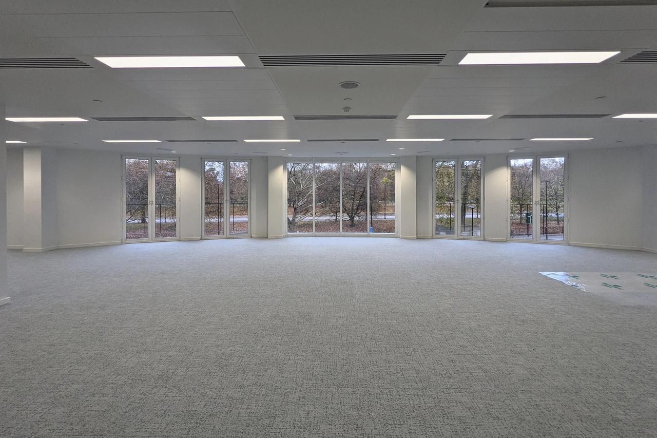 Finished open plan office floor at Knightsbridge with white walls, a grey carpet and windows onto the park