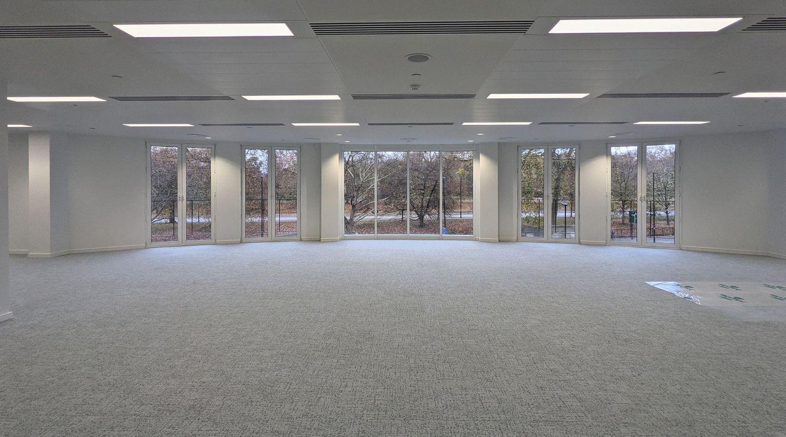 Finished open plan office floor at Knightsbridge with white walls, a grey carpet and windows onto the park