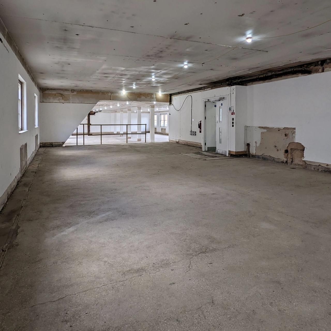 An office floor stripped to bare plaster with exposed joists and no services, March 2022
