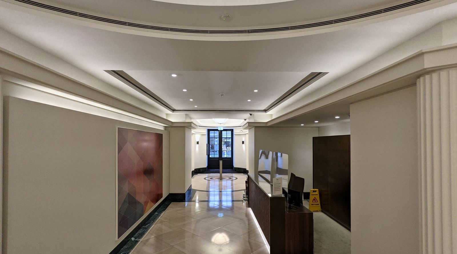 Art deco entrance hall on Jermyn Street with fluted pilasters, a stepped ceiling and a terrazzo roundel floor, looking towards the reception.