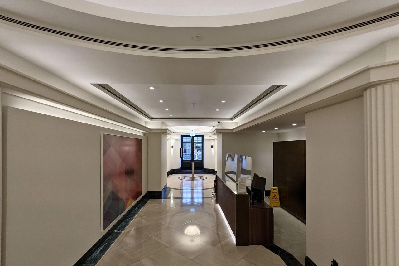 Art deco entrance hall on Jermyn Street with fluted pilasters, a stepped ceiling and a terrazzo roundel floor, looking towards the reception.