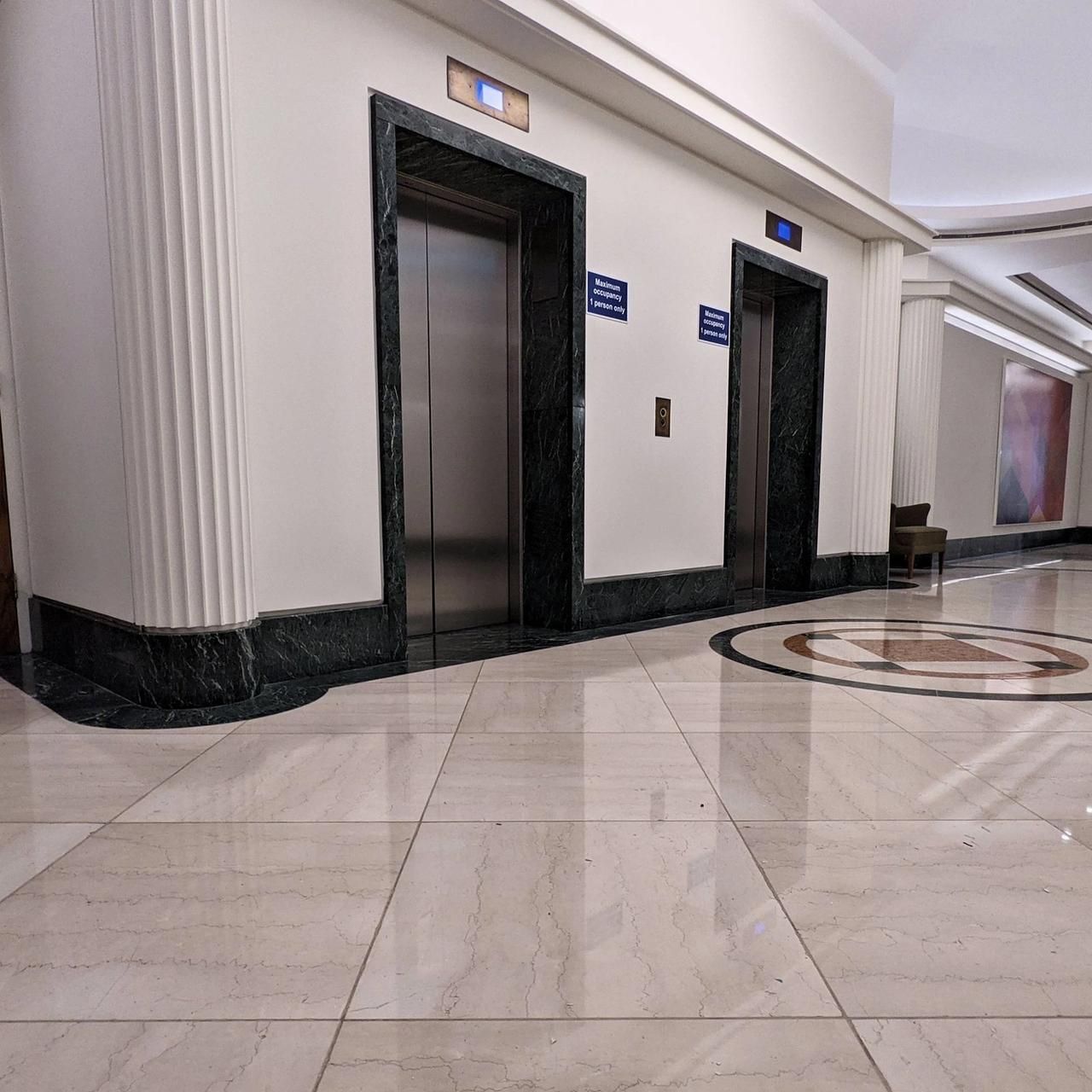 Lift lobby looking towards the entrance with green marble surrounds, painted pilasters and the terrazzo floor